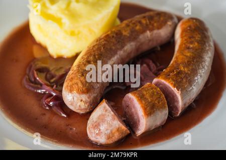 Wildwurst oder Bangers mit Kartoffelbrei und Rotwein und Zwiebelsoße Stockfoto