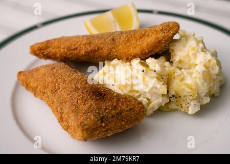 Paniertes Karpfenfilet mit Mayonnaise-Kartoffelsalat und Zitrone, ein traditionelles Weihnachtsgericht in Böhmen und Österreich Stockfoto