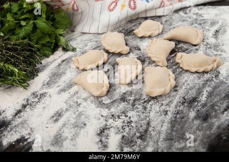 Hausgemachte, handgemachte Knödel auf rustikalem Hintergrund mit Kräutern Stockfoto