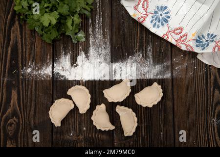 Hausgemachte, handgemachte Knödel auf rustikalem Hintergrund mit Kräutern Stockfoto