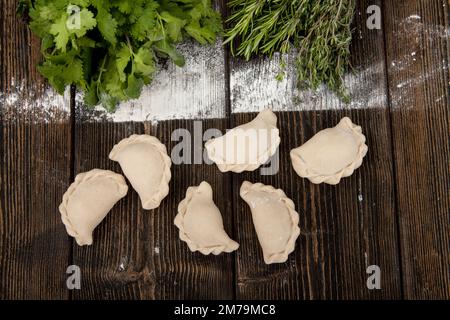 Hausgemachte, handgemachte Knödel auf rustikalem Hintergrund mit Kräutern Stockfoto