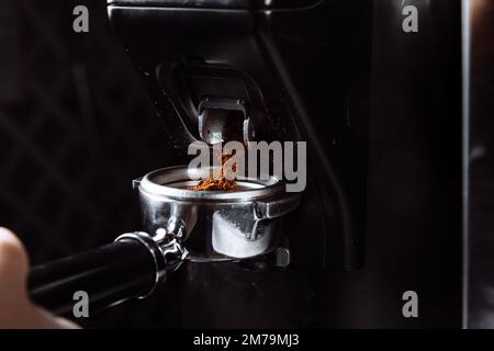 Frisch gemahlener Kaffee, der vom Mahlwerk in den Portafilter fällt. Zubereitung eines Espresso Stockfoto