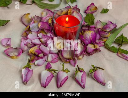 Getrocknete Rosen, Kerze und Buch auf einem Tuch Stockfoto