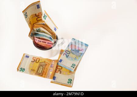 Gerollte Euro-Banknoten in einem weißen Becher mit weißem Hintergrund und Kopierbereich Stockfoto