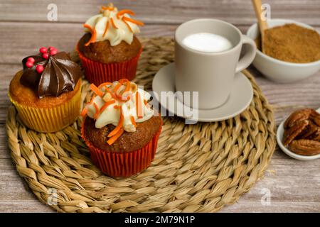 Auswahl an Schokolade-, Sahne- und Karotten-Cupcakes mit verschiedenen Hintergründen Stockfoto