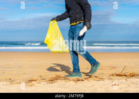 Meeresverschmutzung, nicht erkennbare Person, die Plastik im Sand am Strand sammelt. Ökologiekonzept Stockfoto