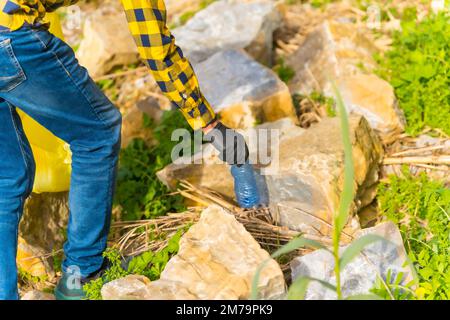 Unbekannte Person, die Kunststoffe in einem Wald sammelt. Umweltkonzept, Recycling Stockfoto