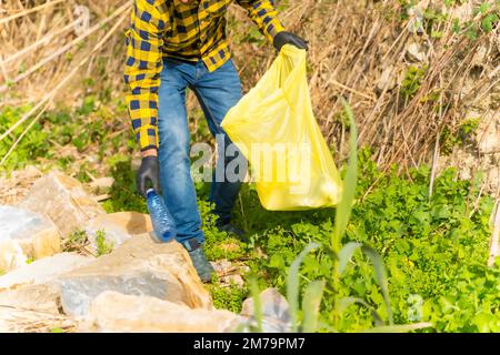 Unbekannte Person, die Kunststoffe in einem Wald sammelt. Umweltkonzept, Recycling Stockfoto