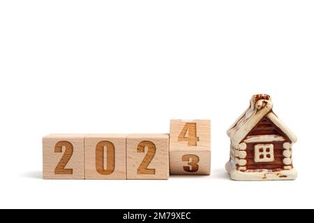 Holzwürfel mit der Aufschrift 2023 verwandeln sich in 2024 und Haus auf weißem Hintergrund Stockfoto