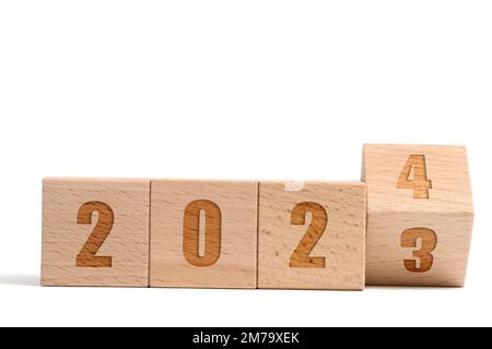 Holzwürfel aus Buche mit der Aufschrift 2023, die sich in einen weißen 2024-Hintergrund verwandelt Stockfoto
