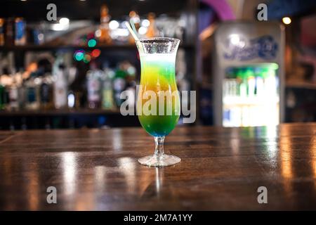 Glas mit einem kühlen fruchtigen Cocktail mit Strohhalm im Hintergrund der Bar im Restaurant Stockfoto