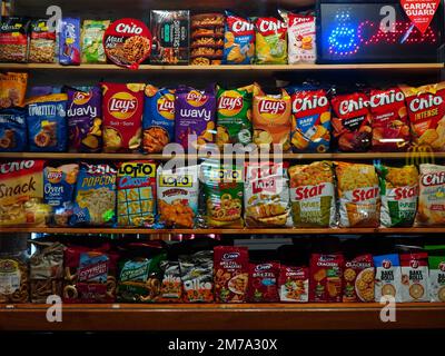 Beutel mit Snacks verschiedener Marken auf Regalen im Fenster des Food Kiosks im Nordbahnhof in Bukarest, Rumänien, am 24. November 2022 Stockfoto