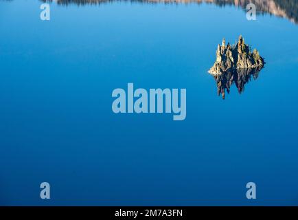 Phantom Ship spiegelt sich im Sommer in den blauen Gewässern des Crater Lake wider Stockfoto