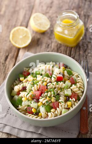 Frischer, hausgemachter, farbenfroher veganer Nudelsalat mit Bohnen, Mais, Tomaten, Gurke und grünem Paprika, serviert in der Schüssel Stockfoto