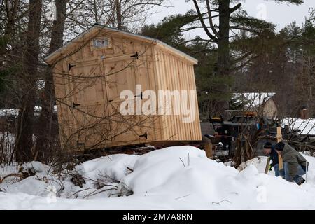 Ein vorgefertigter Holzschuppen, der nach einem schweren Schneesturm angeliefert und in Betrieb genommen wird Stockfoto