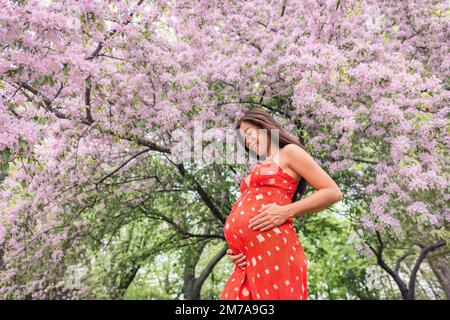 Schwanger Frau glücklich Porträt in mit Frühlingsblumen. Neue Saison und neues Lebenskonzept. Schwangerschaft in 3. Trimester. Asiatische Frau erwartet Baby Gefühl Stockfoto