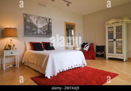 Queen-Size-Bett und weißer Holzschrank mit Gitterrahmen im Gästezimmer im oberen Stockwerk im modernen kubistischen Stil Haus. Stockfoto