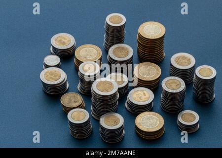 Stapel mexikanischer Pesos-Münzen, isoliert in der Mitte des Bildes mit blauem Hintergrund. Stockfoto