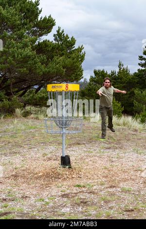 Ein Mann mit dunkler Sonnenbrille spielt Disc-Golf im South Beach State Park in Newport, Oregon, USA. Stockfoto