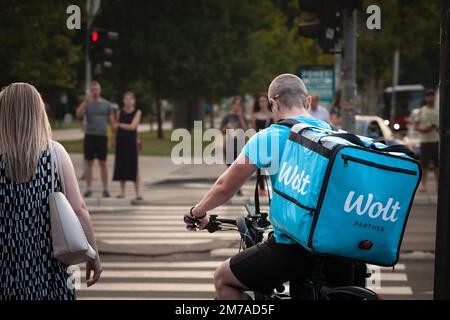 Bild eines Lebensmittellieferanten aus Wolt, der durch die Straßen von Belgrad, Serbien, radelt. Wolt ist ein finnisches Technologieunternehmen, das für sein Food-D bekannt ist Stockfoto