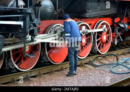 Am 07. Januar 2023 in Kiew, Ukraine, überprüft der Arbeiter die mechanischen Teile eines retro-Dampflokomotivradsatzes am Hauptbahnhof. Stockfoto