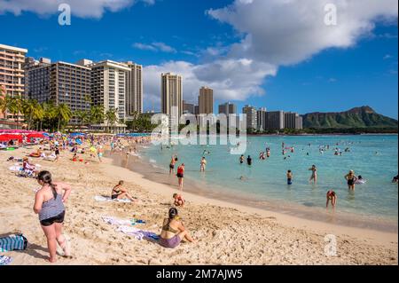 Honolulu, Hawaii - 28. Dezember 2022: Geschäftiger Waikiki Beach an einem wunderschönen Tag in den Weihnachtsferien. Stockfoto