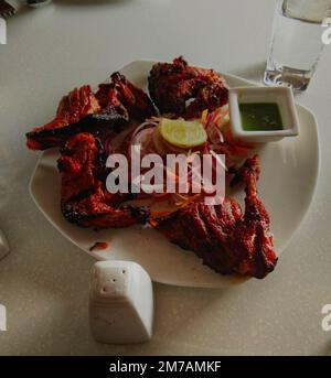 Hühnchen Tandoor Gericht mit Zitrone, Salat, Salz, grünem Chutney auf indische Art. Stockfoto