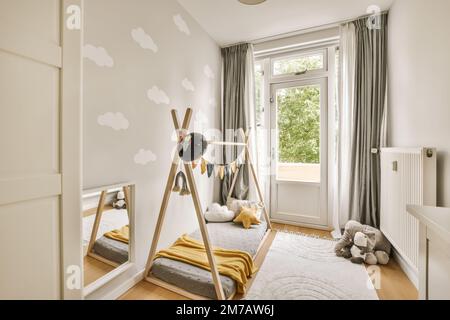 Ein Kinderzimmer mit Wolken an der Wand und Holzmöbeln in der Ecke, inklusive Kinderbett Stockfoto