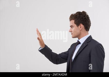 Die Welt der Enitre liegt Ihnen zu Füßen. Ein gutaussehender junger Geschäftsmann, der mit einer transparenten digitalen Schnittstelle interagiert. Stockfoto