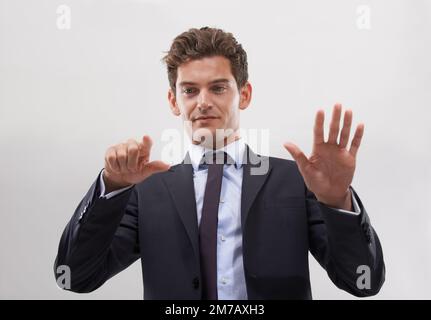 Die ganze Welt steht Ihnen jetzt zur Verfügung. Ein gutaussehender junger Geschäftsmann, der mit einer transparenten digitalen Schnittstelle interagiert. Stockfoto