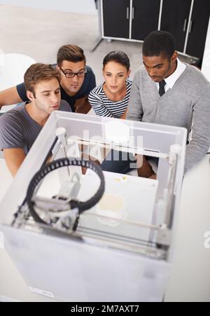 Fasziniert von moderner Technologie. Eine Gruppe von Designern, die sich einen 3D-Drucker ansehen. Stockfoto