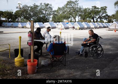 Tampa, Florida, USA. 30. Dezember 2022. Die Bewohner des Tampa Hope Shelters verbringen die Zeit damit, an einem Tisch in der Nähe der Zelte zu plaudern. (Kreditbild: © Robin Rayne/ZUMA Press Wire) Stockfoto