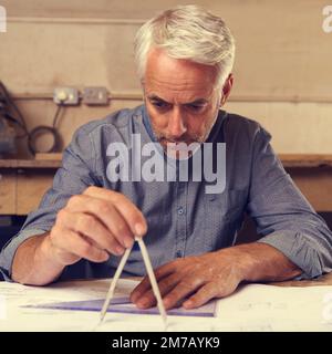 Er ist stolz auf seine Genauigkeit. Ein Zeichner, der ein Dreieck und einen Kompass benutzt, um Baupläne zu erstellen. Stockfoto