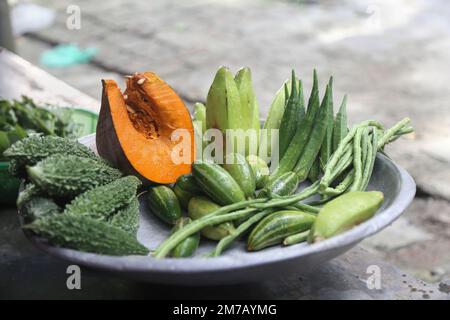 Eine Sammlung von bunten Gemüsesorten, die Kürbis, Bitter Gourd, Grüne Banane und Marienfinger enthalten, ist eine gute Nahrungsquelle für Kinder. Stockfoto