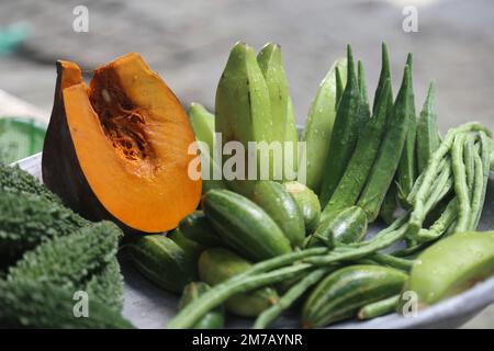 Eine Sammlung von bunten Gemüsesorten, die Kürbis, Bitter Gourd, Grüne Banane und Marienfinger enthalten, ist eine gute Nahrungsquelle für Kinder. Stockfoto