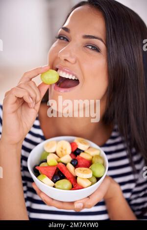 Voller Aroma. Porträt einer jungen Frau, die Obstsalat isst. Stockfoto