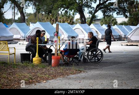 Tampa, Florida, USA. 30. Dezember 2022. Die Bewohner des Tampa Hope Shelters verbringen die Zeit damit, an einem Tisch in der Nähe der Zelte zu plaudern. (Kreditbild: © Robin Rayne/ZUMA Press Wire) Stockfoto