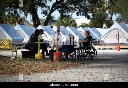 Tampa, Florida, USA. 30. Dezember 2022. Die Bewohner des Tampa Hope Shelters verbringen die Zeit damit, an einem Tisch in der Nähe der Zelte zu plaudern. (Kreditbild: © Robin Rayne/ZUMA Press Wire) Stockfoto