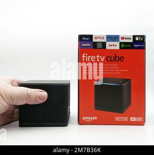 Menschliche Hand hält einen Amazon Fire TV Cube isoliert auf weißem Hintergrund. Stockfoto