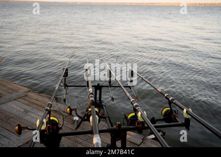 Professioneller Stand mit Angelruten auf dem Pier, Sommerangeln Konzept. Stockfoto