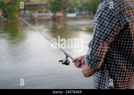 Fischer mit Rote, Drehrolle am Flussufer. Sonnenaufgang. Sommermorgen. Ländlicher Kurzurlaub. Stockfoto