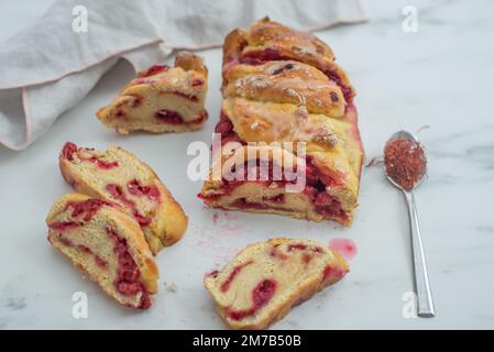 Süße hausgemachte Safran-Baba-Brioche mit Himbeeren auf einem Tisch Stockfoto