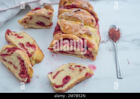 Süße hausgemachte Safran-Baba-Brioche mit Himbeeren auf einem Tisch Stockfoto