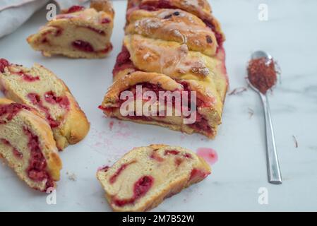 Süße hausgemachte Safran-Baba-Brioche mit Himbeeren auf einem Tisch Stockfoto