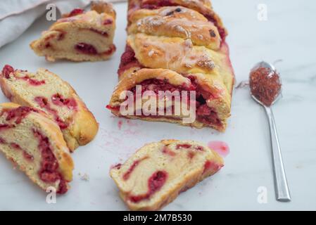 Süße hausgemachte Safran-Baba-Brioche mit Himbeeren auf einem Tisch Stockfoto