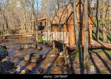 Idyllische Blockhütten an einem Bach im Wald im Frühjahr Stockfoto