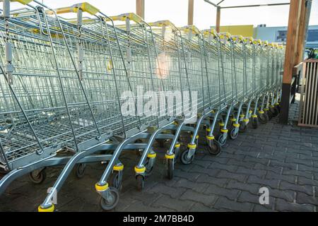 Eine Reihe großer Einkaufswagen auf Rädern, Blick an sonnigen Tagen Stockfoto