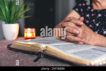 Eine alte Frau liest die Bibel, die Hände sind dicht. Stockfoto