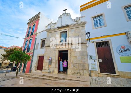 Von der Außenfassade aus hat man einen Blick auf den Steineingang. In der katholischen Kirche Ermida de Nossa Senhora da Conceição, Kapelle in Loulé, Algarve, Portugal Stockfoto