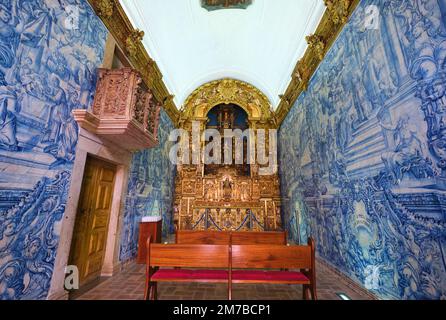 Innenansicht der kleinen Kapelle mit reich geschnitzten, goldenen Holzaltar und dem berühmten Azulejo, blauen Fliesenwänden. In der Ermida de Nossa Senhora da Conceic Stockfoto